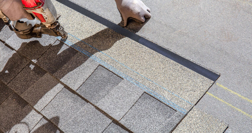 A worker nailing shingles on to a new roof.