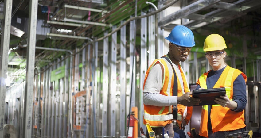 Two workers using tablet on site. 