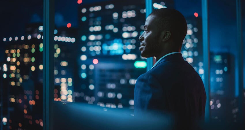 Man looking out a building at the night skyline