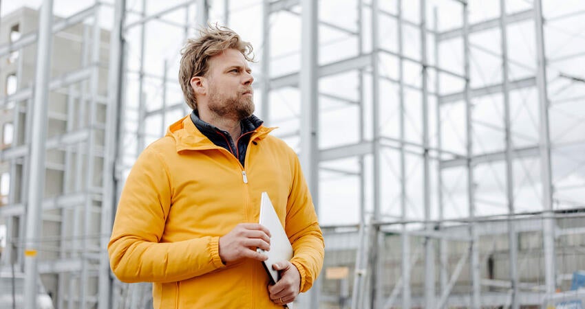 Man in yellow coat outside a glass building
