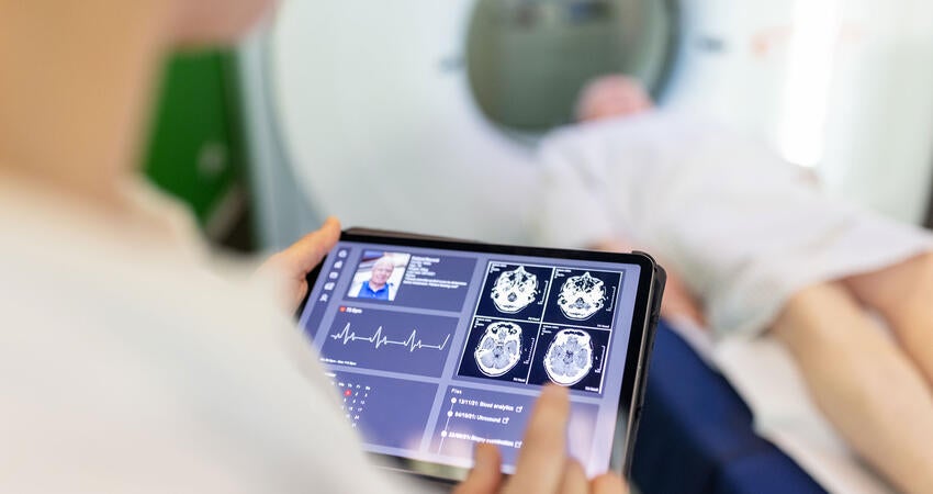 Neurologist examining patient's CAT scan images on digital table in a clinic