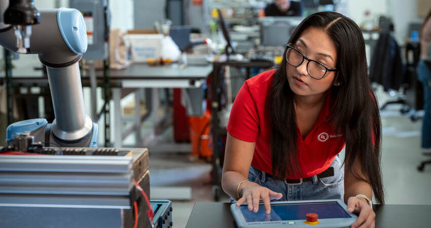 Engineer in red UL Solutions polo troubleshooting a robot arm