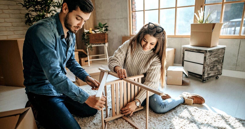Two people working together to assemble a wooden chair