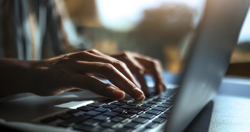 Hands typing on a laptop