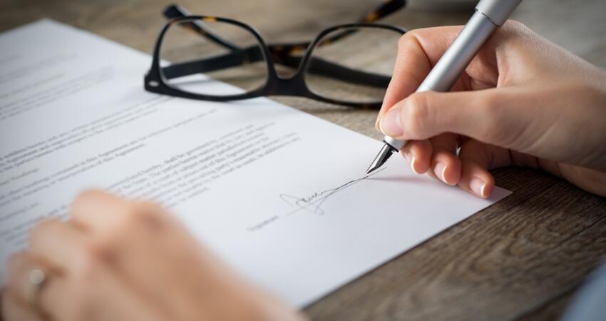 A hand signing a document