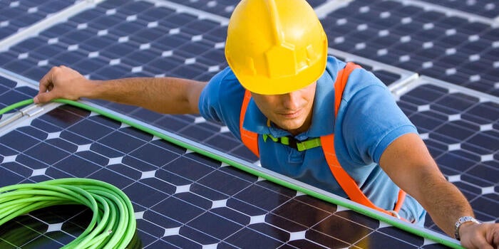 man in hard hat doing wiring on a solar energy panel for wire and cable testing and certification