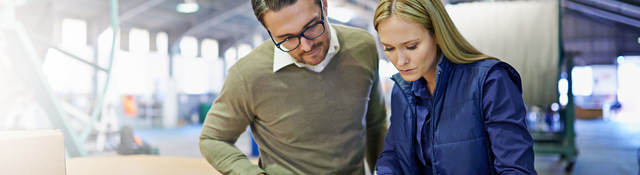 A Man and a woman look at something together in workplace