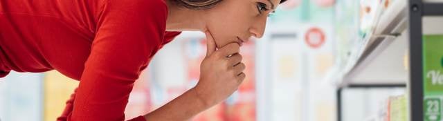 Brown-haired woman looks carefully at a shelf filled over-the-counter medications.