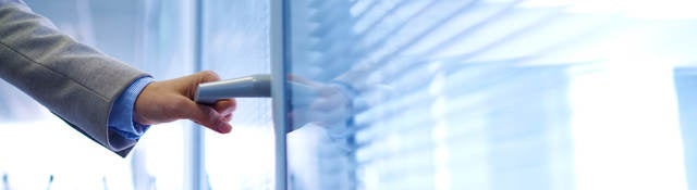 photo of a hand opening an office door, with people in background.