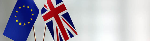 European union and British flag pair on a desk over defocused background