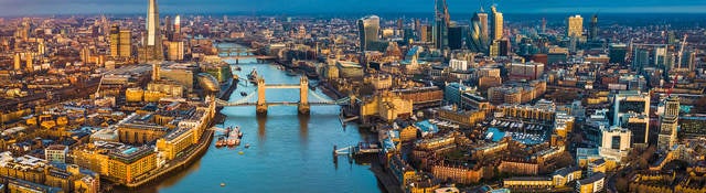 Golden hour aerial view of London’s skyline, including the Tower Bridge and famous skyscrapers.