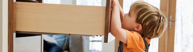 A child pulling on an open dresser drawer, a furniture tip-over risk