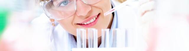 Female scientist dripping liquid into vials 