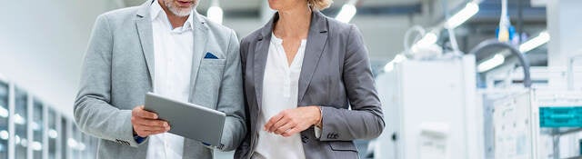 Two workers collaborating on a device while walking