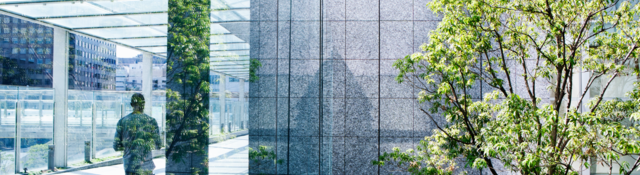 Silhouettes of a green tree and a business man walking on a passage through glass