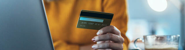 woman holding a credit card and sitting in front of a laptop computer