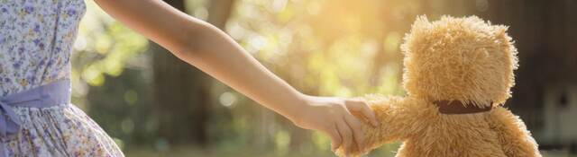 Young girl holding hands with a teddy bear