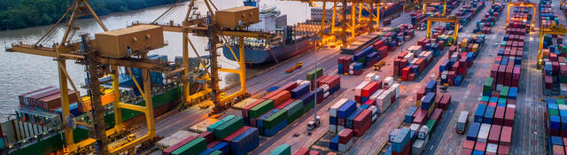 Container cargo ship and cargo plane with working crane bridge in shipyard at sunrise