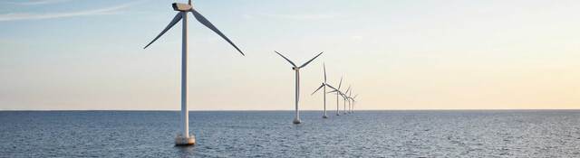 A row of wind turbines stretching across a body of water