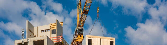 Crane lifting a prefabricated wooden building module to its position in the structure