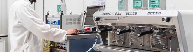 Laboratory technician conducting test on espresso machine.