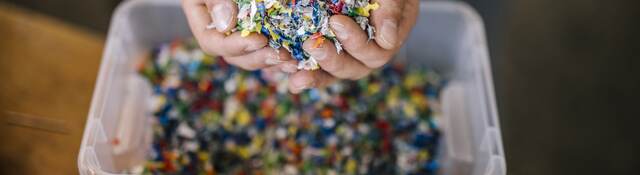 Man with container holding recycled plastic in factory