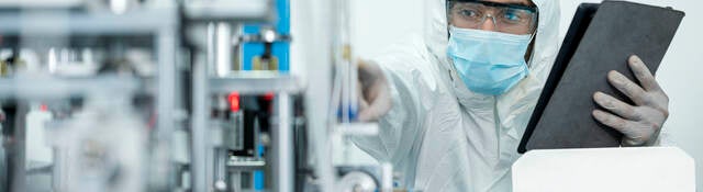 Shot of Caucasian Engineers using digital tablet for inspection quality of producing protective face mask in automated production line.