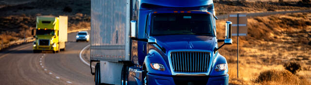 A semi truck driving down a highway at dusk