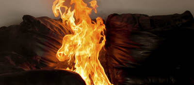 A flame rises off of a couch.