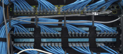 A close-up image of blue ethernet cable plugged into a data center. 