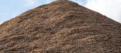 Pile of mulch woodchips against a blue sky