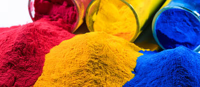 Magenta, yellow and cyan powders spill out of glass jars next to each other.