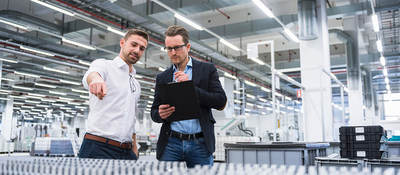 Two men consulting over pallets of plastic products