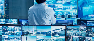 Person standing in a control room looking at security video feeds