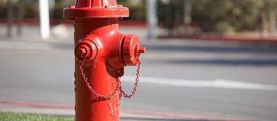 A bright red fire hydrant along a road.