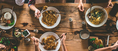 Bird’s-eye view of young people eating around a dinner table