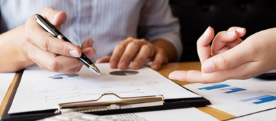 Closeup of hands writing on a clipboard at a meeting