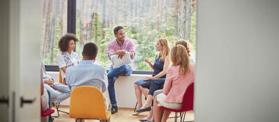 Group of people in an office space sitting in a circle for a meeting