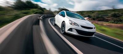 White car cornering in mountain road with speed blur