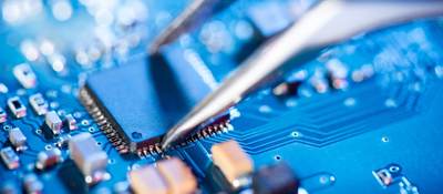 A pair of specialized tweezers places a circuit on a board