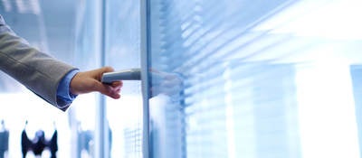 photo of a hand opening an office door, with people in background.