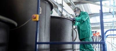 Worker at mixing tanks in chemical factory