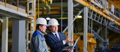 Two men in warehouse looking at laptop