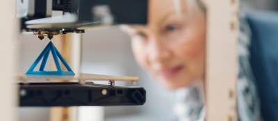 Photo of a woman working by a 3D printer