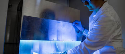 A woman uses UV light to inactivate harmful material on products.