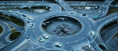 Autonomous self-driving cars moving in a traffic circle next to a highway. 