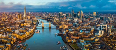 Golden hour aerial view of London’s skyline, including the Tower Bridge and famous skyscrapers.