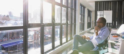 Pensive businessman looking out sunny office window