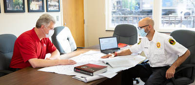 Two code authorities sitting at a table together looking at building plans.