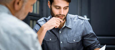 Two male business professionals reviewing documentation at workplace.